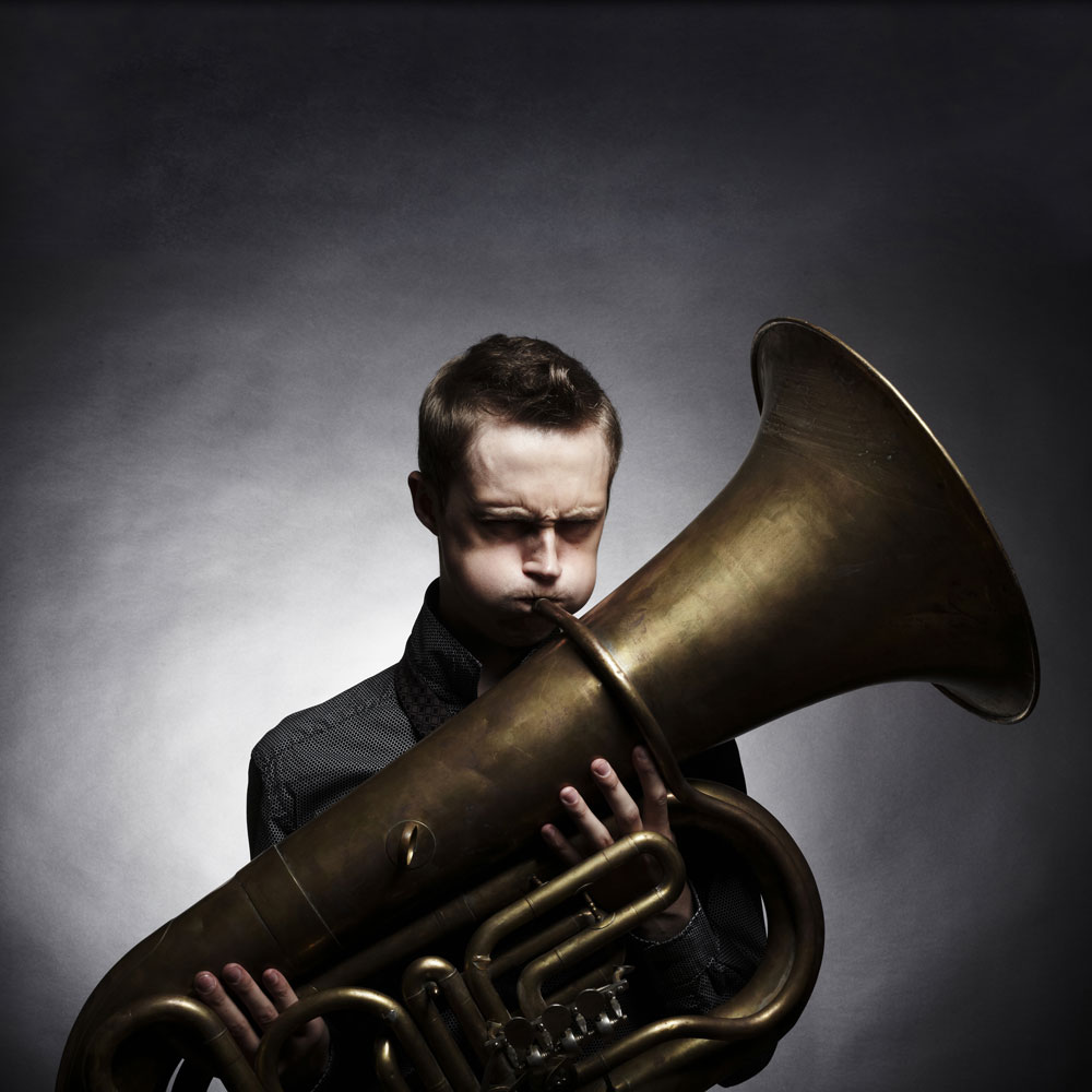 Jeune musicien soufflant dans un tuba, prêt à jouer sa partie