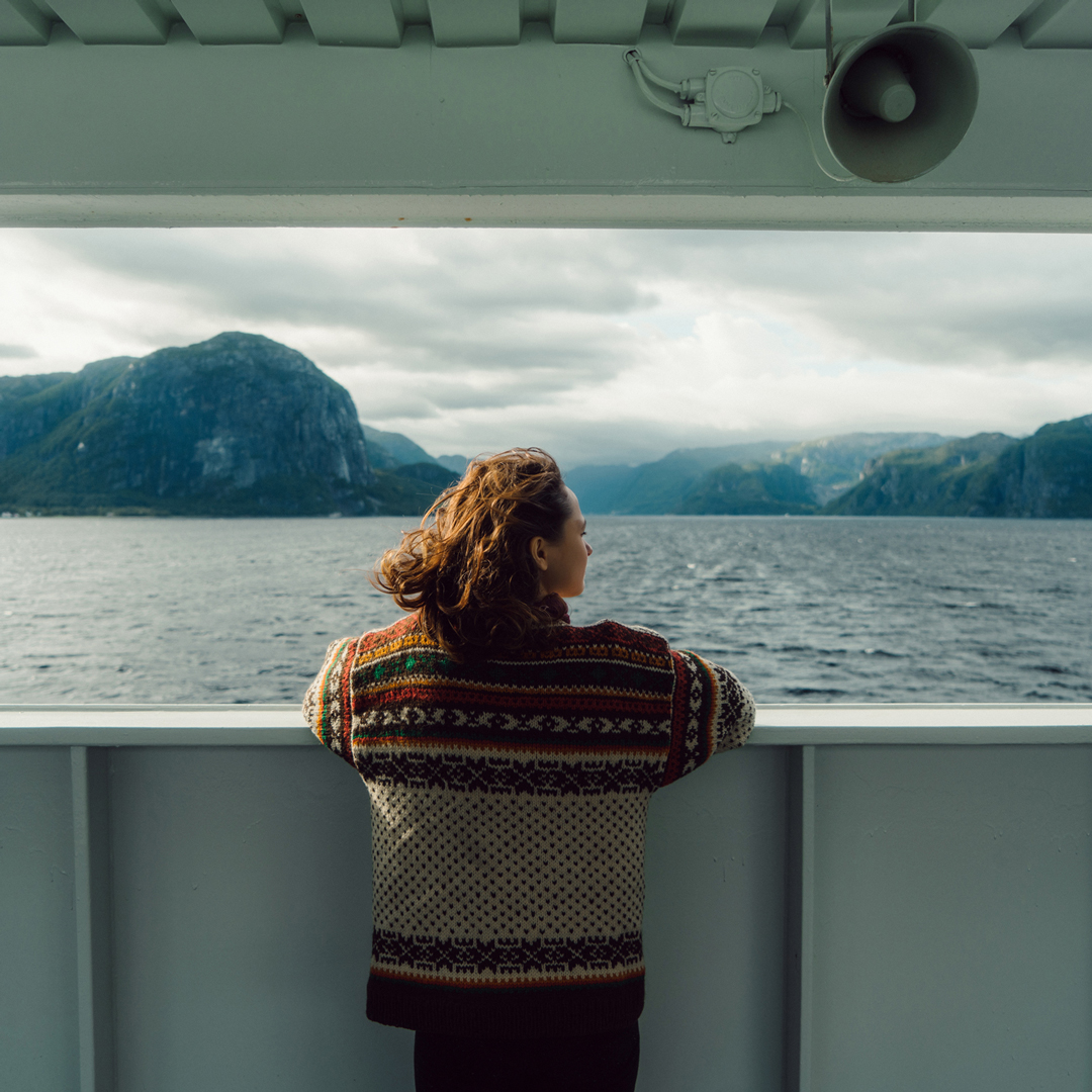 Femme accoudée au bastingage d'un bateau, face à un fjord : la destination d'un projet entrepreneurial
